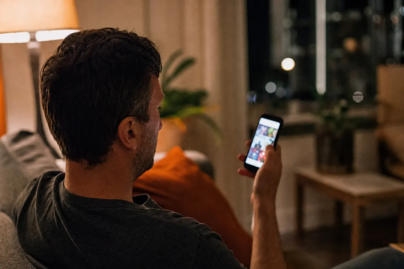 A homeowner on a couch looking at a social media feed on his smartphone